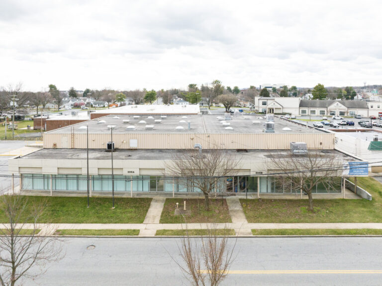 One story 1960s building from an aerial view, and the building has glass paneling and doors with pillars