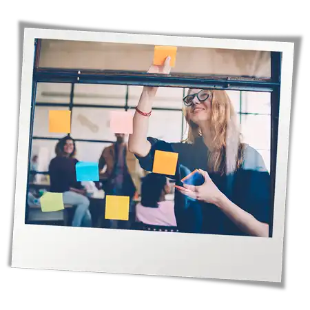 Leader in meeting placing post-it notes on window to facilitate collaboration between youth-serving