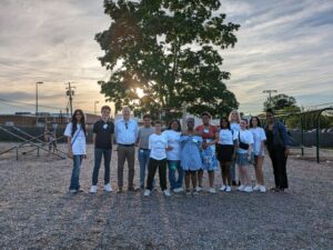 Youth Council at a playground with the sun setting in the background between a swing set and seesaws