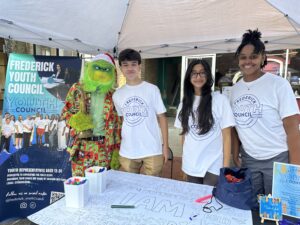 3 members of the Youth Council standing next to the Grinch